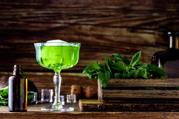 Vibrant green cocktail with mint in a cristal glass. Classic cocktail front of wooden background