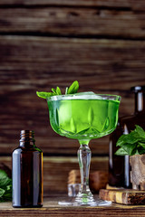 Vibrant green cocktail with mint in a cristal glass. Classic cocktail front of wooden background