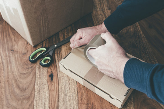 close-up of person sealing up shipping box with parcel tape, pruchase return and return of goods concept