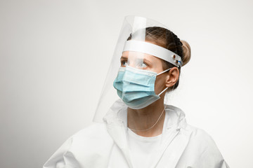 Fototapeta na wymiar young woman in medical mask and protective shield on her head looking away.