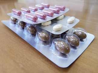 pink capsules, white pills, brown dragees are on the table in the hospital