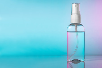 Small bottle of instant hand sanitizer mist spray. Antibacterial alcohol antiseptic liquid in transparent plastic container with atomizer pump on gradient background, no label. Copy space for text.