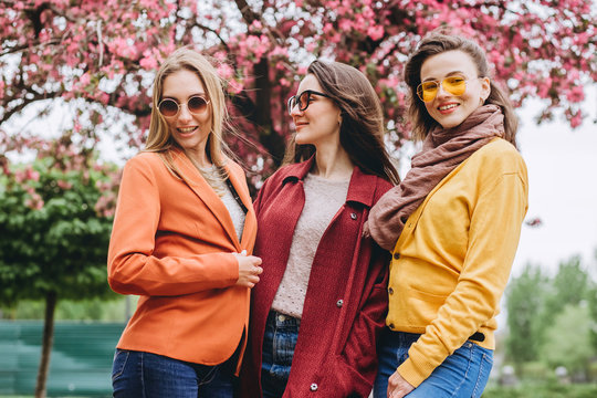 Best friends girls having fun, joy. Lifestyle. Beautiful young women in sunglasses dressed in the nice clothes smiling on a sunny day. photos of girls against the background of flowering trees