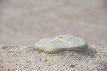 ein einzelner weißer Stein im feinen Sand