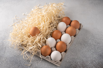 Brown and white chicken eggs in a eco-friendly package from paper and straw on light textured background