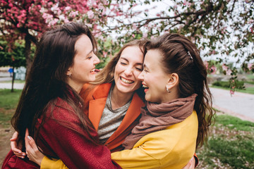 Best friends girls having fun, joy. Lifestyle. Beautiful young women in sunglasses dressed in the nice clothes smiling on a sunny day. photos of girls against the background of flowering trees