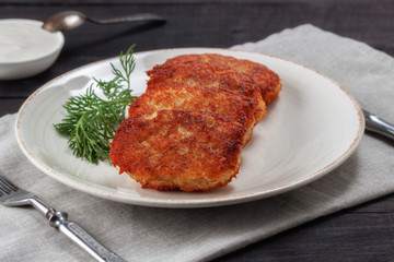 Potato pancakes with sour cream and dill on a wooden table