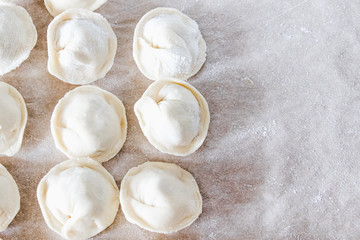 Raw dumplings with minced meat on the table. The process of making homemade dumplings.