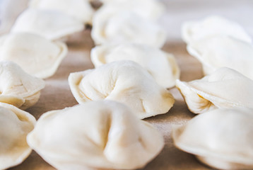 Raw dumplings with minced meat on the table. The process of making homemade dumplings.