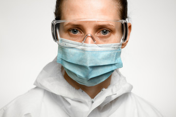 woman with blue eyes in medical mask and goggles for protection against influenza.