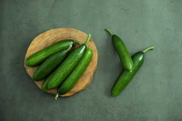 Organic mini cucumber on wooden serving plate ready to eat. Freshly harvested healthy and delicious food. Top view, flat lay.
