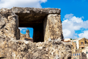 Abstract city view, architectural detail of an old building in the Matera old town as seen through blurred stone fence frame in Matera, Province of Matera, Basilicata Region, Italy