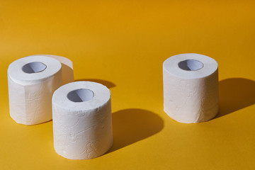 Creative still life with rolls of toilet paper, hot commodity during covid-19 and period of self isolation. Yellow background, copy space