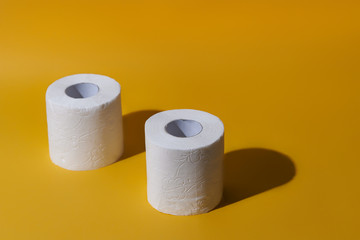 Creative still life with rolls of toilet paper, hot commodity during covid-19 and period of self isolation. Yellow background, copy space
