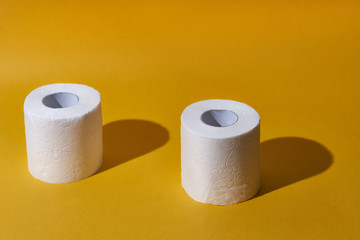 Creative still life with rolls of toilet paper, hot commodity during covid-19 and period of self isolation. Yellow background, copy space