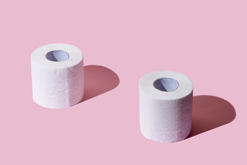 Creative top view image with rolls of toilet paper, hot commodity during covid-19 and period of self isolation. Pink background, copy space