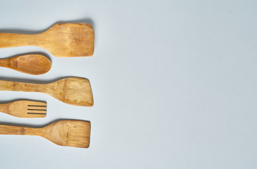 Collection of wooden kitchen utensils over grey background.