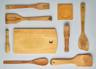 Wooden kitchen utensils and accessories for cooking on grey background.