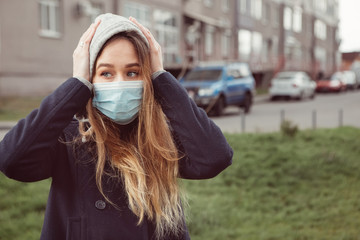 Closeup portrait of a girl in a medical mask on the street, epidemic of a coronavirus. Woman with coronavirus symptoms. The man violated the rules of self-isolation. SARS-CoV-2. COVID-19.