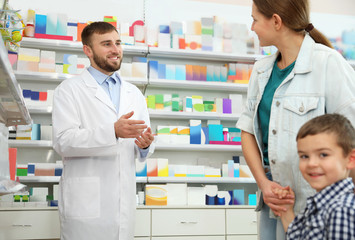 Professional pharmacist working with customer in modern drugstore