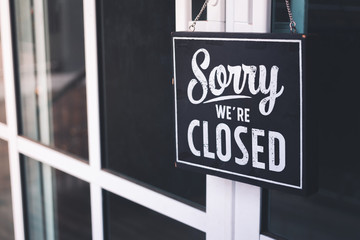 Sorry we're closed sign. grunge image hanging on cafe glass door.