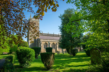 Fototapeta na wymiar The Church of St Peter and St Paul on a bright sunny day framed by trees and foliage in the small somerset town of Wincanton