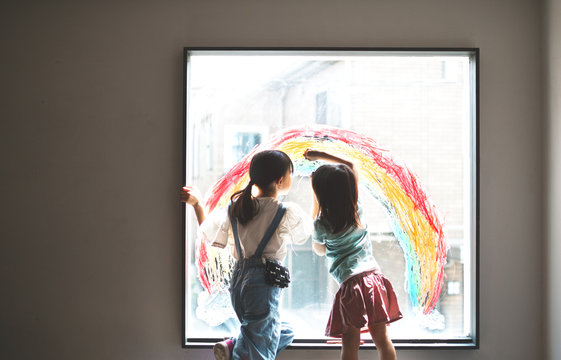 大きな窓に大きな虹を描く姉妹　