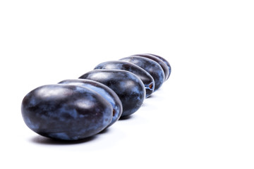 Fresh blue plums, isolated on white background, in close-up.