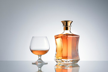 close up view of bottle of whiskey and a glass aside on grey back. 
