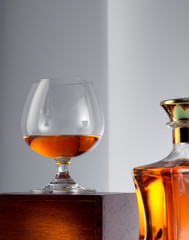 close up view of bottle of whiskey and a glass aside on grey back. 