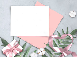 Mock up feminine concept  with empty paper blank, gift and ribbons heart on grey background. Elegant still life flatlay for Mothers day, Womans day or wedding invitation.