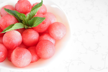 Fruit salad of watermelon balls and green mint in a bowl close-up