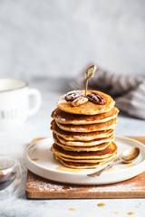 Homemade classic american pancakes with pecans and maple syrup, served with fingerfood sticks. Stack of small pancakes with bamboo brochettes on light grey background. American cuisine.