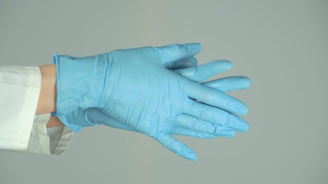 Splatters of spray antiseptic on blue medical gloves.On a white background.Compliance with sanitary rules and norms against viruses and diseases.Sprays disinfectant inside.Hands closeup.The nCoV virus