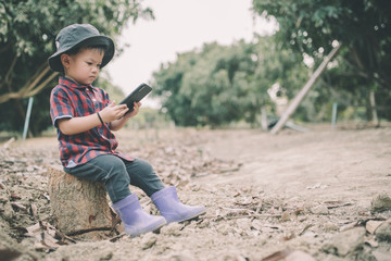 A cute little farmer in Asia wears a red shirt working through a mobile phone. The concept of agribusiness