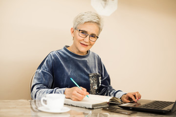 stylish woman with a short haircut sits at a table with a laptop