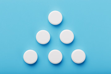 Round medicinal tablets in the shape of a triangle on a blue background, isolate.