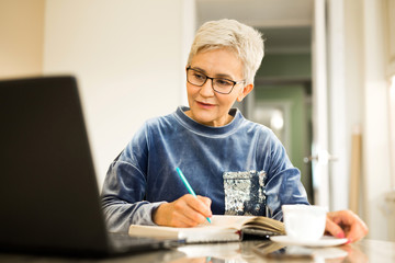 stylish woman with a short haircut sits at a table with a laptop