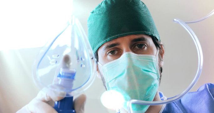Punto di vista di un paziente mentre viene intubato con la mascherina di ossigeno da un dottore in sala operatoria durante il Coronavirus.