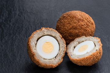 Scotch eggs on black stone background