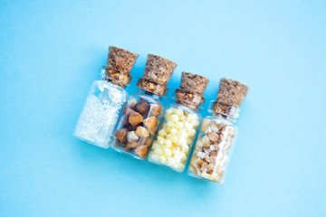 Picture with soft focus of four tiny glass jar with buckwheat, millet, sugar and barley on blue background, top view. Concept of nutrition, vegetarian products. Empty space for text and design