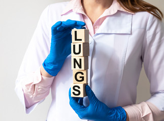 LUNGS word on cube blocks in hands in medical gloves of a female doctor