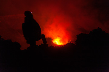 A tourist looking at the glowing lava of Nyiragongo volcano