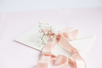 Envelope on a white-pink background with peach silk ribbon and pink flowers. Wedding invitation. Mother's day card. Place for text. Copy space