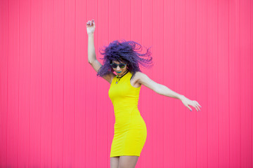 Millennial woman dancing to pop music in the street isolated on pink background. Teenagers...