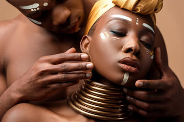 close up view of naked tribal afro couple posing isolated on beige - Powered by Adobe