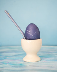 Egg on a white ceramic stand for lilac eggs and a lilac ceramic spoon in a stand with an egg