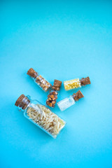 Vertical picture with soft focus of five tiny glass jar with rice, buckwheat, millet, sugar and barley on blue background, top view. Concept of nutrition, vegetarian products. Space for text