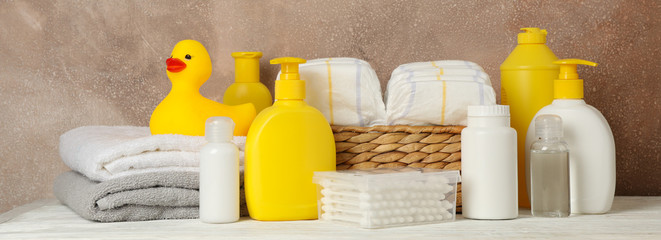 Baby hygiene accessories on wooden table against brown background