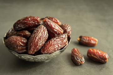 Raw date fruit ready to eat in silver bowl on concrete background. Traditional, delicious and healthy ramadan food.